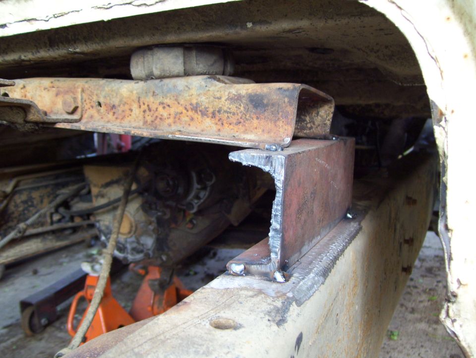 Fabricated steel bracket welded to frame rail supporting rusty crossmember under a truck