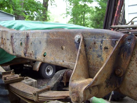 1972 Ford F-150 - A close-up view of a heavily rusted truck frame, showing chalk marks for modification.