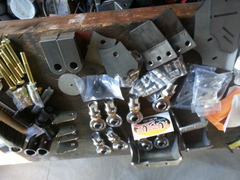 1978 Ford Bronco - Various metal suspension components and hardware are organized on a workbench.