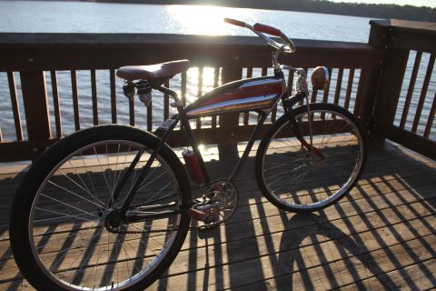 1994 Ford Bronco - A vintage bicycle with a distinctive red and chrome tank is parked on a wooden deck overlooking the water.