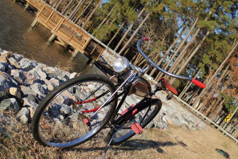 1994 Ford Bronco - A vintage bicycle rests near the water's edge, with a wooden pier and trees visible in the background.