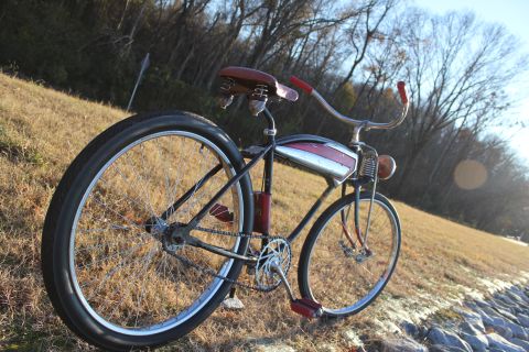 1994 Ford Bronco - A vintage cruiser bicycle with a chrome and red tank sits on a grassy embankment near the water.