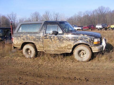 1996 Ford Bronco - A 1996 Ford Bronco is covered in mud after off-roading in a field with other vehicles.