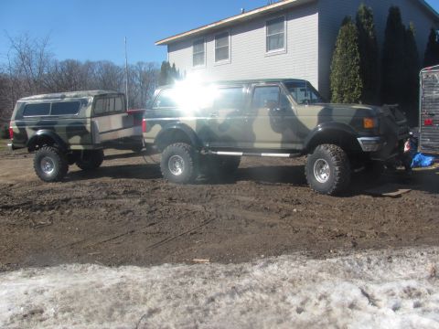 1996 Ford Bronco - A camouflaged Ford Bronco tows a matching trailer on a muddy lot.