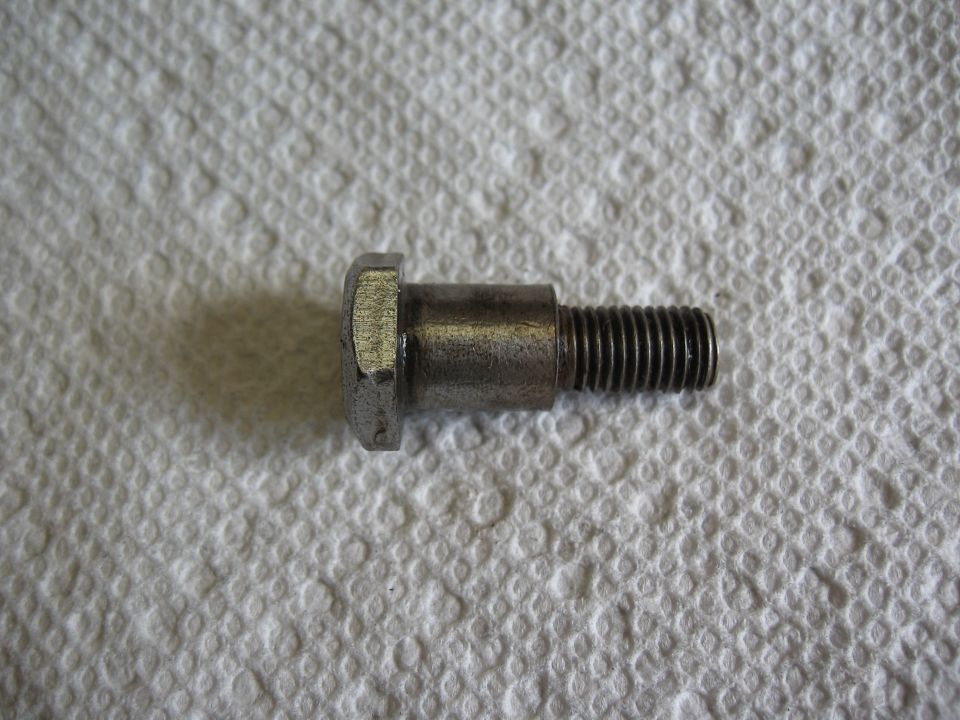 Metal bolt with hex head and threaded shaft, lying on a white paper towel