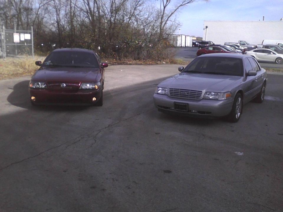 Silver 2003 Ford Crown Victoria parked in front of a maroon sedan