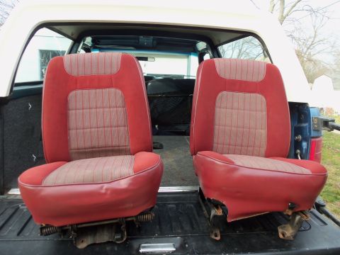 1985 Ford Bronco - Interior car seats with red and tan fabric upholstery are shown removed from the vehicle.