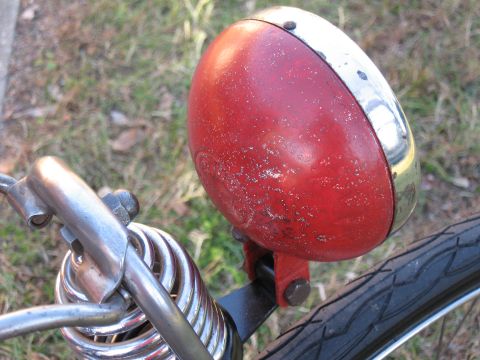 1994 Ford Bronco - Close-up of a vintage red bicycle headlight with chrome trim and suspension springs.