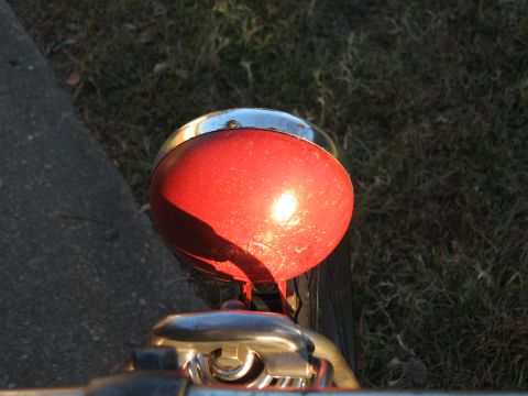 1994 Ford Bronco - A close-up view of a red motorcycle headlight with chrome trim, set against a grassy background.