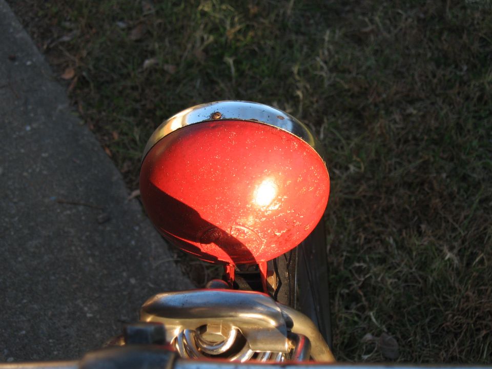 Red motorcycle headlight with chrome trim, viewed from above