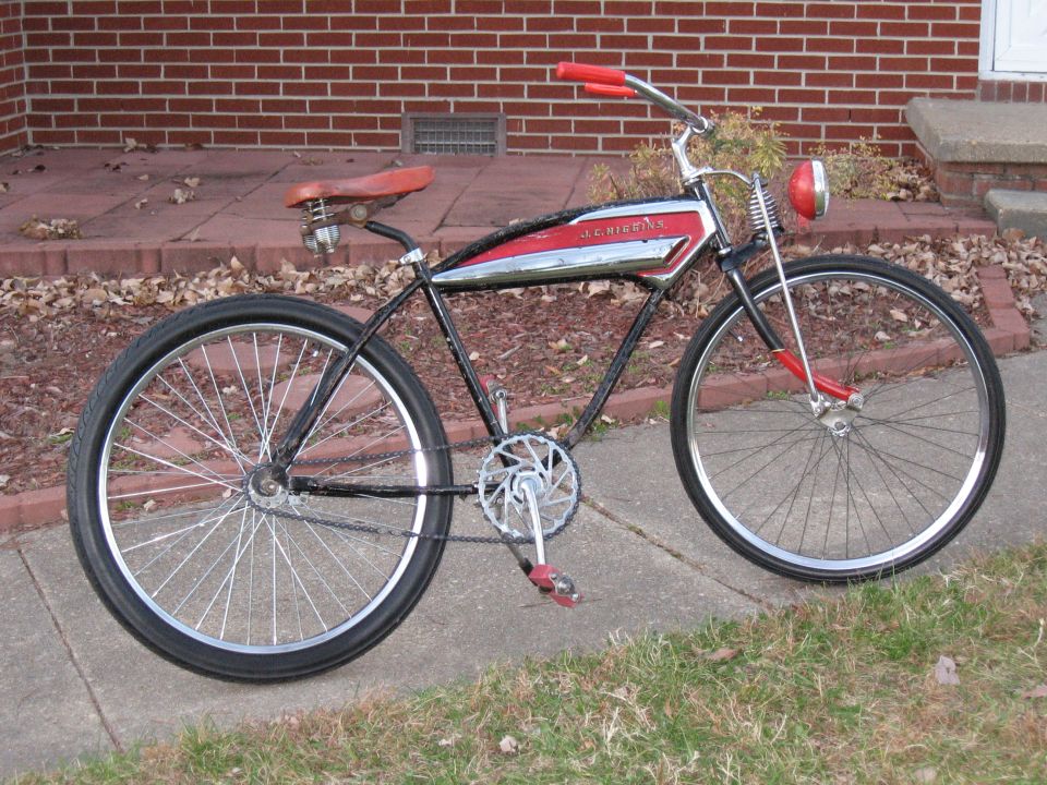 Side view of a vintage black and red bicycle with chrome accents and a red headlight