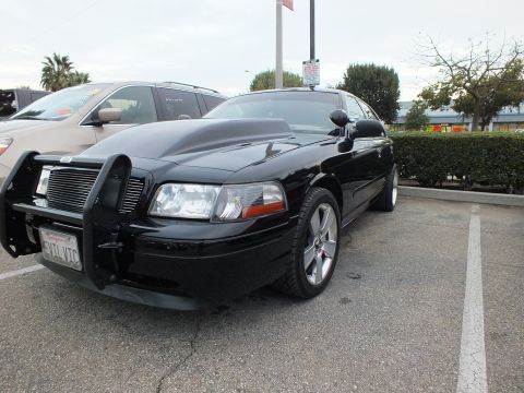 2003 Ford Crown Victoria - Front quarter of a black Crown Victoria fitted with a brush guard and EVIL VIC plate, chrome wheel visible