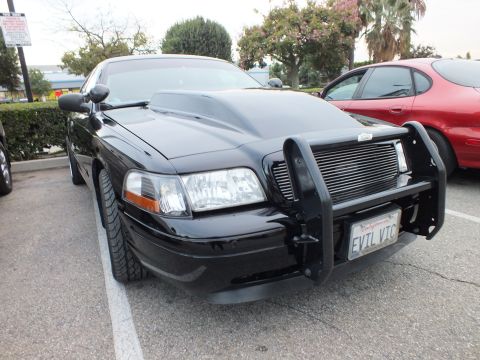 2003 Ford Crown Victoria - Crown Victoria nose with black push bar and chrome billet grille, California EVIL VIC plate, red car parked alongside