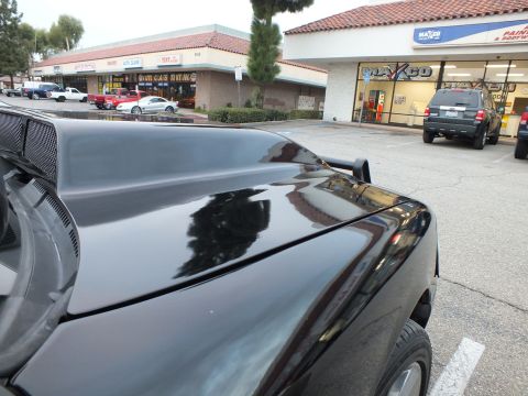 2003 Ford Crown Victoria - Close view across the black hood of a Crown Victoria, Maxco storefront and parked cars reflected in the paint