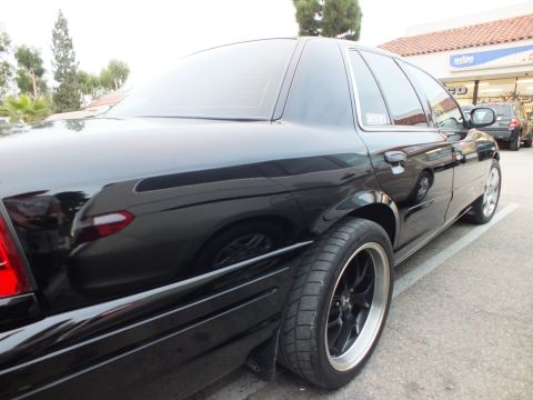 2003 Ford Crown Victoria - Black Crown Victoria shot from the right rear, dark mesh wheels and a sticker on the rear quarter glass