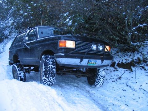 1988 Ford Bronco - A black Ford Bronco navigates a snowy trail with its front wheels turned.