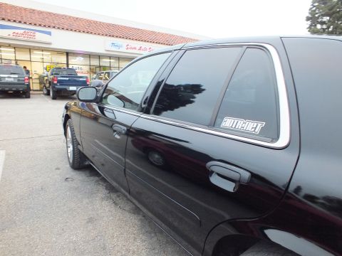 2003 Ford Crown Victoria - Black Crown Victoria rear door and window with a white decal, Tony's Siam Auto storefront in the background