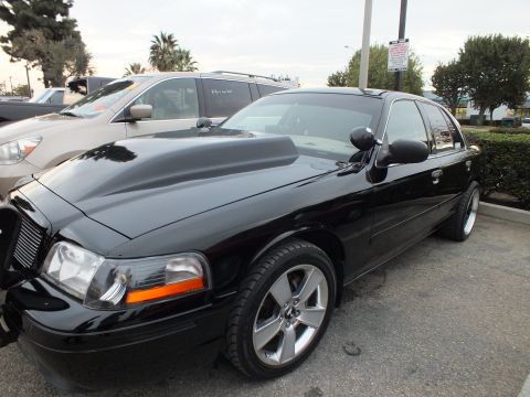 2003 Ford Crown Victoria - Front three-quarter of a lowered black Crown Victoria with chrome multi-spoke wheels and billet grille