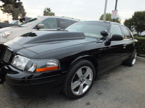 2003 Ford Crown Victoria - Lowered black sedan with a chrome waterfall grille and five-spoke chrome wheels seen from the front left