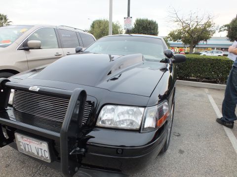 2003 Ford Crown Victoria - Front of a black Crown Victoria with brush guard and EVIL VIC California plate, person standing at the right