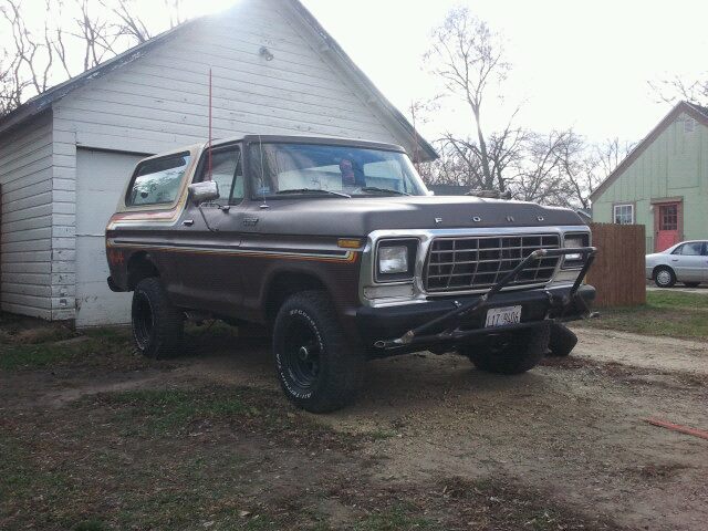 1979 Ford Bronco parked in front of a garage, with a custom bumper and aftermarket wheels
