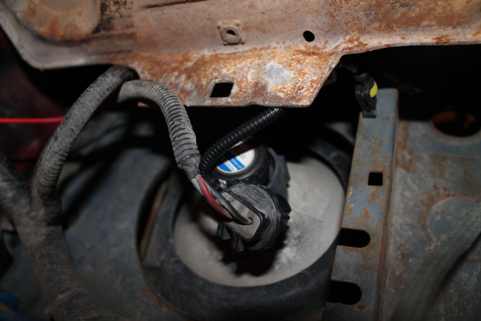 Close-up of rusty metal frame with electrical wires and a headlight assembly