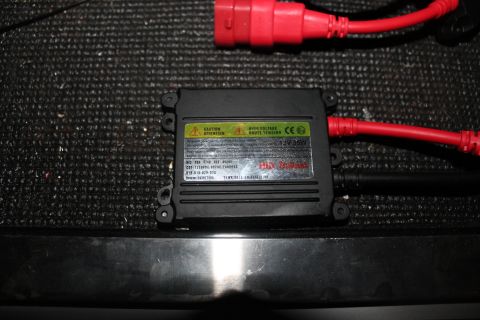 1990 Ford Bronco - A close-up shows a black HID ballast with warning labels and red electrical connectors.