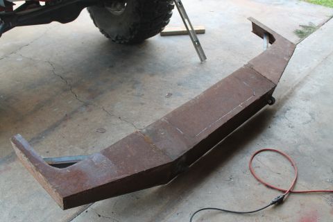 1990 Ford Bronco - A custom-fabricated steel bumper lies on a concrete floor, showing signs of rust and fabrication marks.