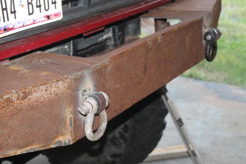 1990 Ford Bronco - A heavily rusted, custom-built rear bumper with integrated tow hooks is attached to a vehicle.