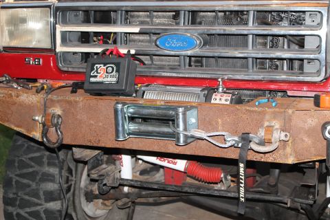1990 Ford Bronco - A close-up view of the front bumper and winch system on a red Ford Bronco.