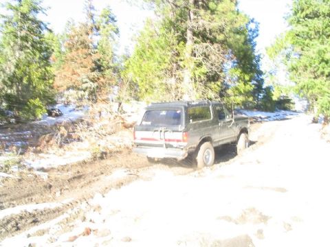 1988 Ford Bronco - Ford Bronco navigates a challenging off-road trail with mud and snow.