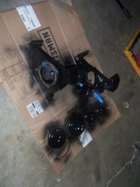 1968 Ford Bronco - Automotive suspension parts and brake rotors are laid out on a cardboard box, some with blue protective caps.