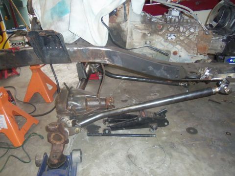 1968 Ford Bronco - The frame of a Ford Bronco is shown with its engine and suspension components, supported by jack stands.
