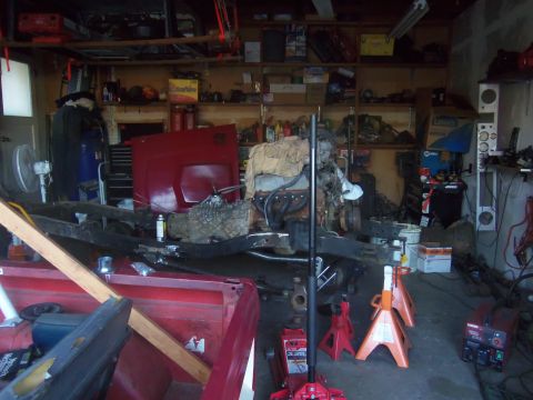 1968 Ford Bronco - A 1968 Ford Bronco is partially disassembled in a garage, with its engine and chassis visible.
