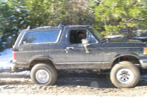 1988 Ford Bronco - A dark blue Ford Bronco navigates a snowy, wooded trail.