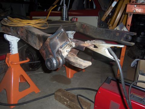 1968 Ford Bronco - Welding is being performed on a vehicle's frame, which is elevated on orange jack stands.