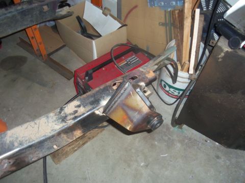 1968 Ford Bronco - A close-up view of a vehicle's frame section, showing modifications and surrounding workshop items.