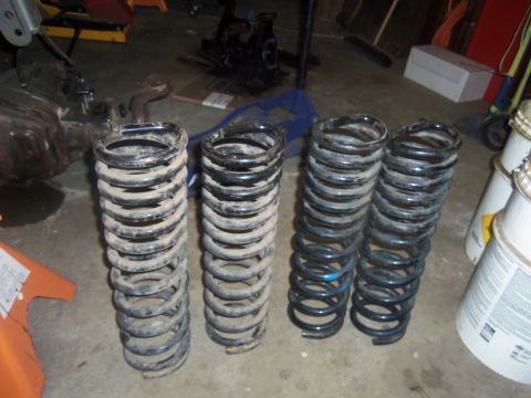 1968 Ford Bronco - Four suspension coil springs are shown on a concrete floor, possibly for a vehicle repair or upgrade.