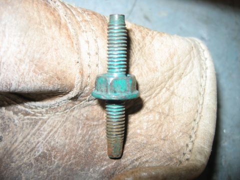 1992 Ford Bronco - A bolt with a green coating and integrated washer is held by a gloved hand, likely for a vehicle repair or maintenance task.