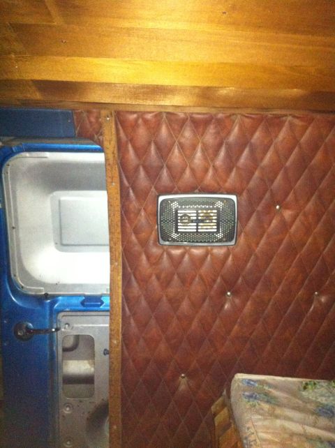 1977 Ford E350 - The interior of a van features diamond-stitched brown upholstery and a metal vent on the wall.
