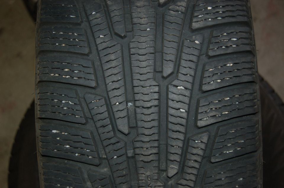 Close-up of a winter tire tread pattern with directional grooves and sipes