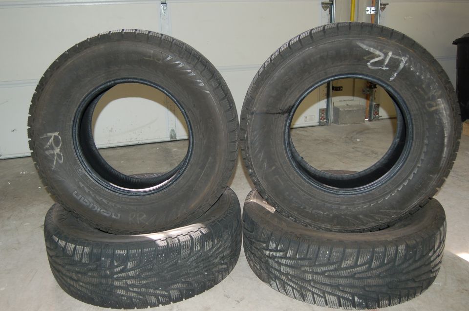 Four stacked tires, two with handwritten markings