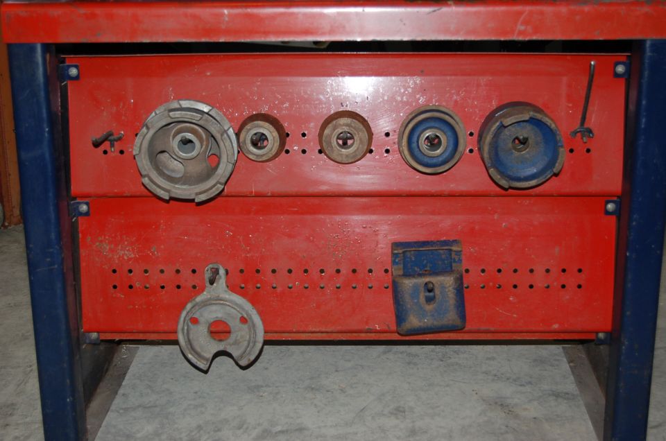 Red metal cabinet with blue frame holding various circular metal tools and a blue lock