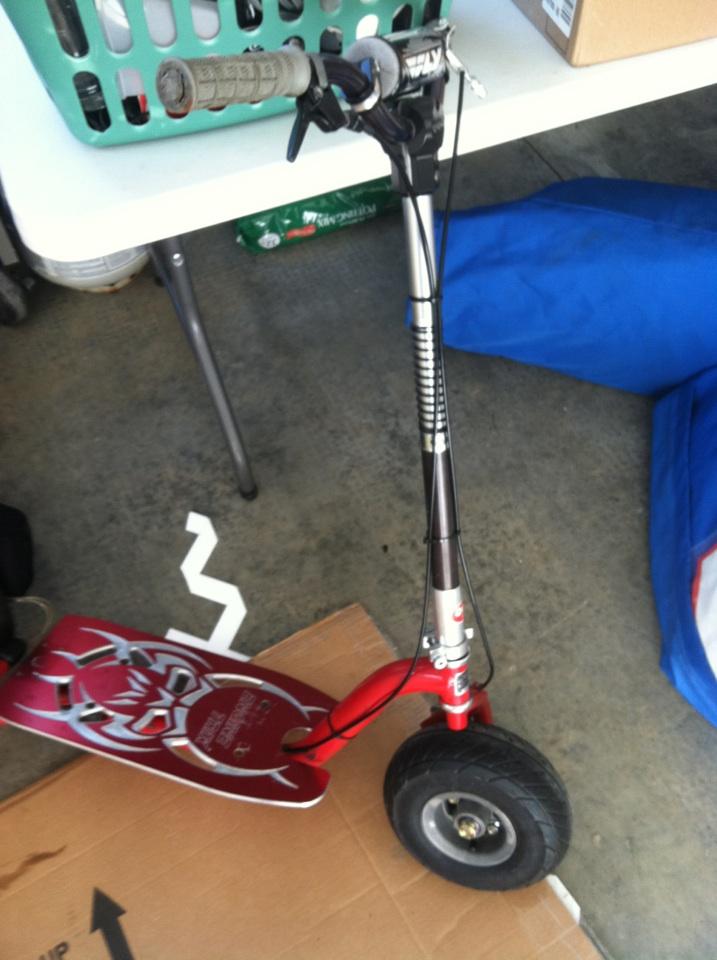 Red electric scooter with black handlebars and a silver telescoping stem