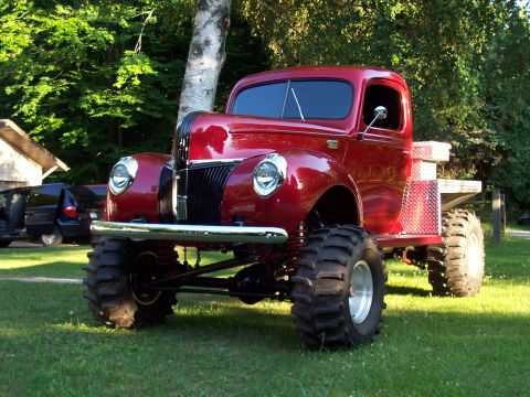 1978 Ford F-150 - This custom pickup truck features oversized tires and a lifted suspension, with other vehicles visible in the background.
