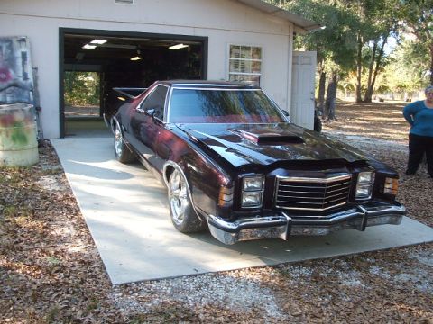 1972 Ford Ranchero - A 1972 Ford Ranchero with a custom hood scoop and chrome wheels is parked on a concrete driveway in front of a garage.
