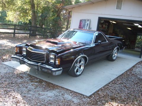 1972 Ford Ranchero - This 1972 Ford Ranchero features a prominent hood scoop and custom chrome wheels, parked outside a garage.