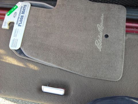 1994 Ford Bronco - A new tan carpeted floor mat embroidered with the "Eddie Bauer" script logo laid on matching tan carpet, still wearing its Ford "Custom Car…