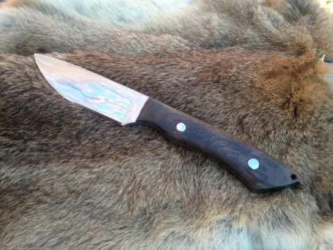 2000 Jeep Wrangler - A knife with a patterned blade and dark handle is displayed on a textured surface.