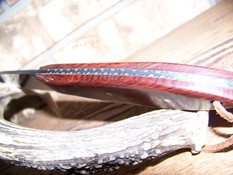 2000 Jeep Wrangler - A close-up view of a knife with a wooden handle and serrated blade, placed on an antler.